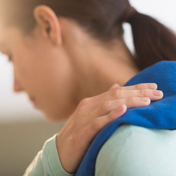 Woman holding heating pad on her shoulder
